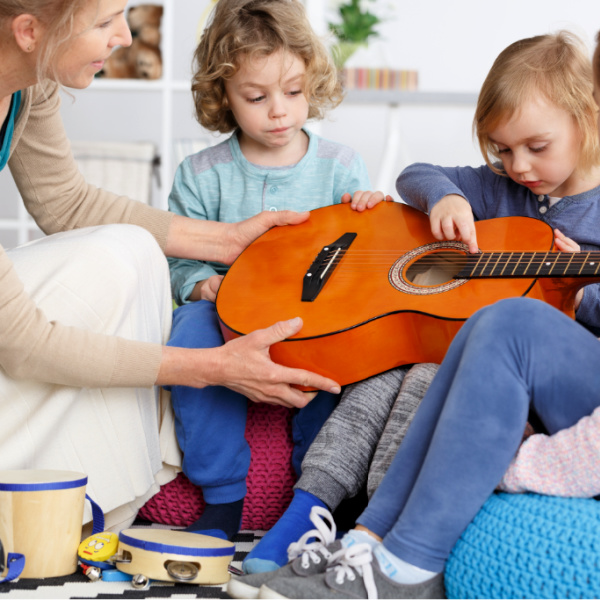 Picture of two young children playing the guitar with their music therapist.