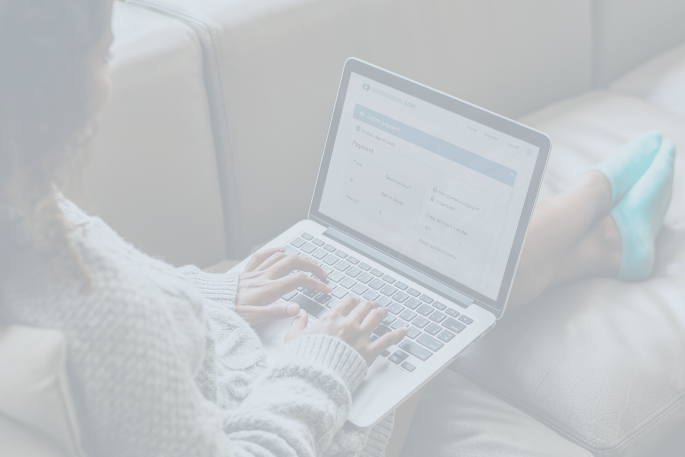 Person sitting on a couch, typing and working on a laptop computer.